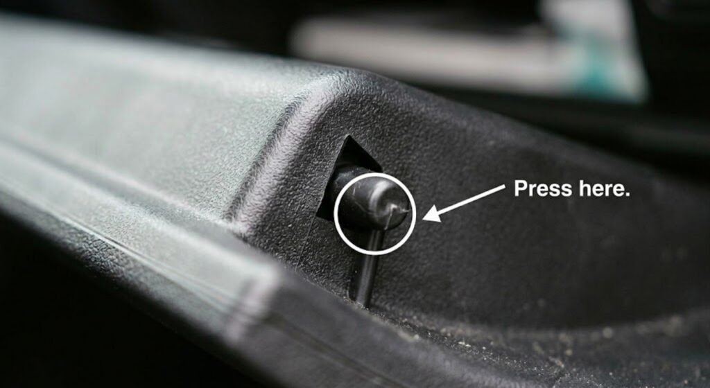 Close-up of 2017 Nissan Rogue cabin filter housing retaining clip showing correct press point at the base of the tab to avoid cracking the plastic